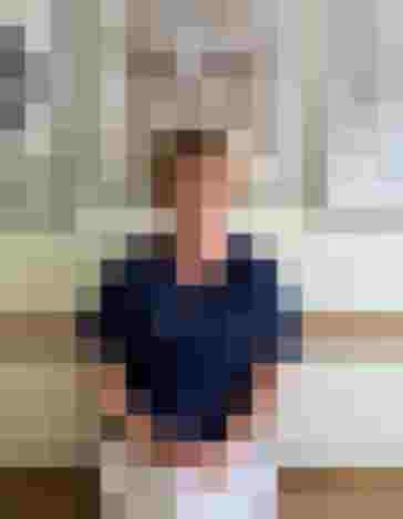 Dr. Ulrike Mack in blauer Uniform, lächelt entspannt vor dekorativen Bildern.