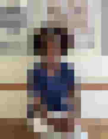 Dr. Ulrike Mack in blauer Praxisbekleidung sitzt entspannt in ihrer Arztpraxis in Salzburg.