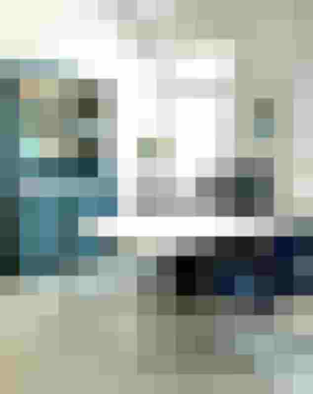 Helle Arztpraxis mit weißen Wänden, blauer Möbelkombination und Pflanzen am Fenster.